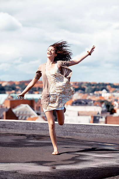 Letting go and living life. Pretty young woman dancing whimsically on a rooftop. - Φωτογραφία, εικόνα