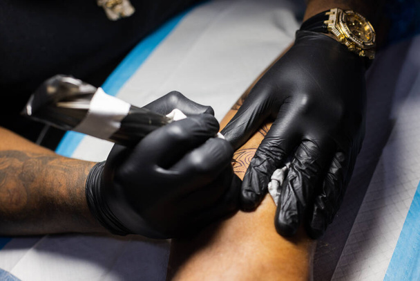 Mãos de tatuador em luvas pretas ocupadas com trabalho. - Foto, Imagem