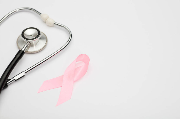 różowa wstążka z rakiem, stetoskop, białe tło, międzynarodowy symbol świadomości raka piersi i moralne wsparcie dla kobiet. Pojedyncze tło, - Zdjęcie, obraz