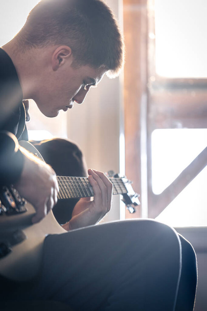 Um jovem toca guitarra elétrica em seu quarto. - Foto, Imagem