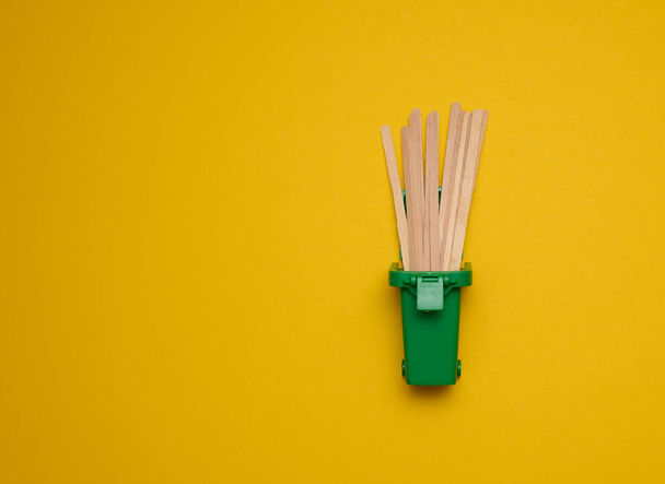 disposable wooden sticks for stirring hot drinks on a yellow background. Coffee and tea spoon, zero waste - Fotoğraf, Görsel