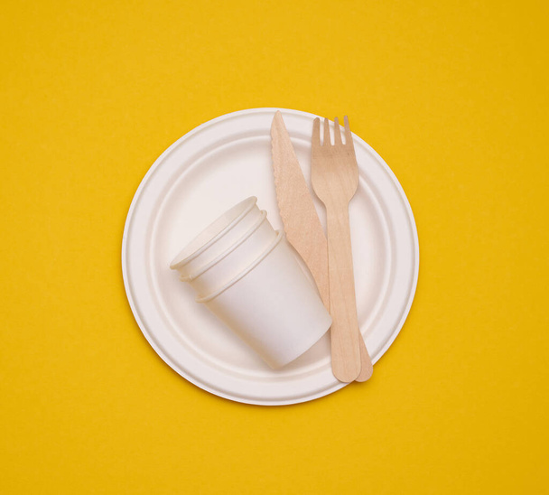 vasos de papel blanco y platos sobre un fondo amarillo. Basura reciclable, rechazo de plástico, vista superior - Foto, imagen