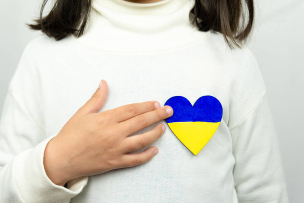 Lapsi, jolla on sydän Ukrainan lipun kanssa. Rauha, lopettakaa sota. - Valokuva, kuva