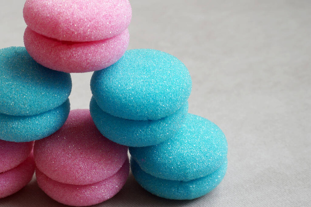 bigodini morbidi in spugna di colore rosa e blu e a forma di biscotti macarons sullo sfondo beige - Foto, immagini
