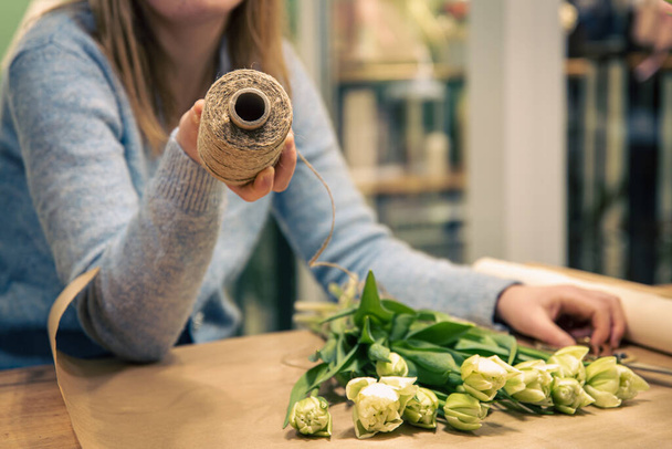 Vrouw bloemist maakt een boeket van tulpen. - Foto, afbeelding