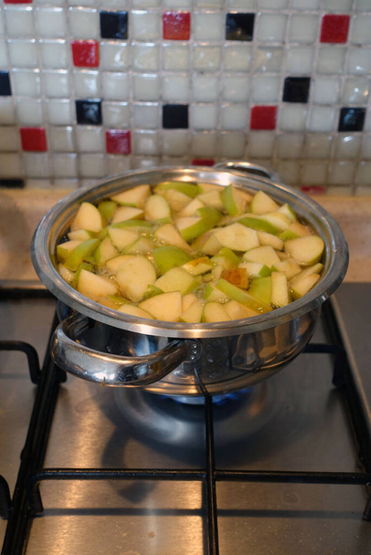 haciendo compota de manzana, trozos de manzana picados hirviendo en una olla, haciendo jugo de manzana casero, - Foto, Imagen