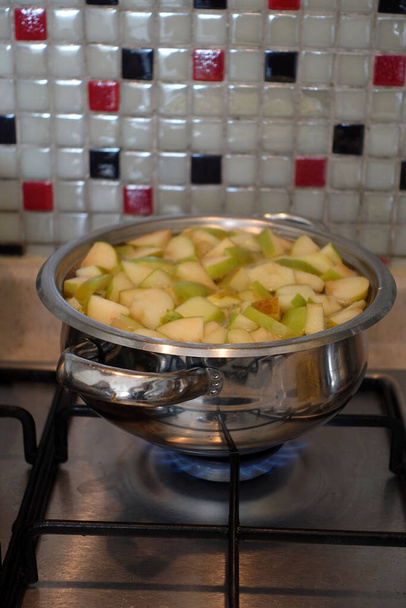 Φρεσκοκομμένα κομμάτια μήλου βρασμένα σε μια κατσαρόλα, κάνοντας σπιτικό χυμό μήλου, - Φωτογραφία, εικόνα