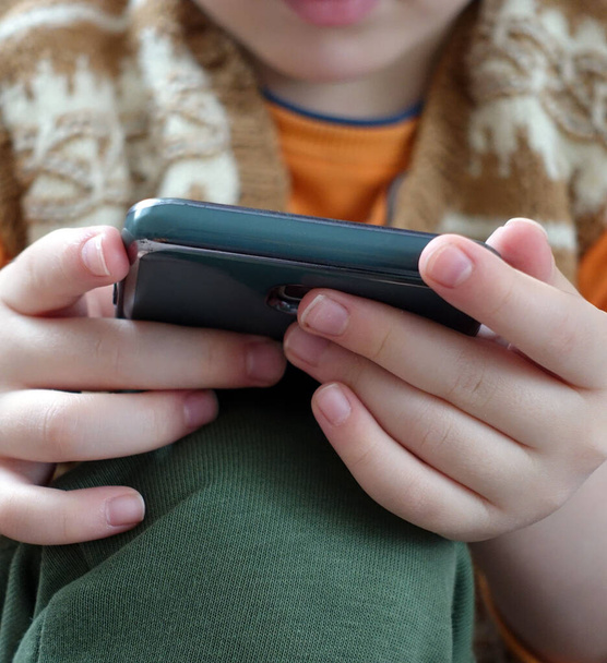крупный план ребенка, играющего со смартфоном, очень крупным планом руки и мобильного телефона, - Фото, изображение