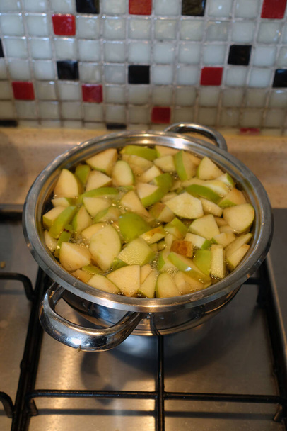 φρεσκοκομμένα κομμάτια πράσινου ξινού μήλου που βράζουν στην κατσαρόλα, φτιάξτε σπιτικό χυμό μήλου, - Φωτογραφία, εικόνα