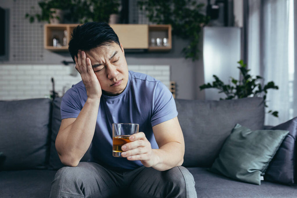 Asian man at home alone, depressed drinking strong alcohol, single man - Foto, Imagen
