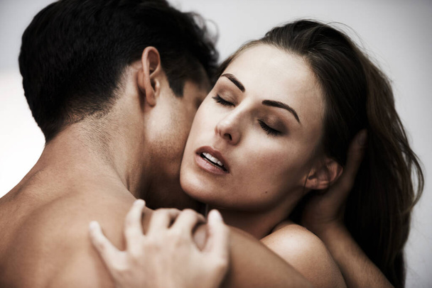 Поглинений пристрастю. Студійний знімок молодої пари, що розділяє інтимний момент на сірому фоні
. - Фото, зображення