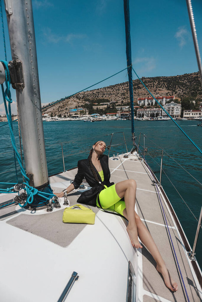fashion outdoor photo of beautiful woman with dark hair in elegant dress posing on the yacht in the sea - Фото, зображення