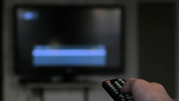 Hand switch channels by remote control. Unfocused TV, close up hand - Footage, Video