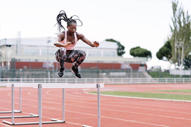 African-American athlete sprinter jumping a hurdle - Valokuva, kuva