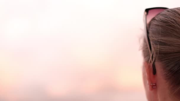 close-up van meisje op zoek naar roze zonsondergang, achteraanzicht. - Video