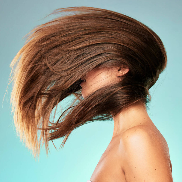 What a fabulous hair flip. Studio shot of an unrecognizable young woman posing against a blue background. - Foto, Imagem
