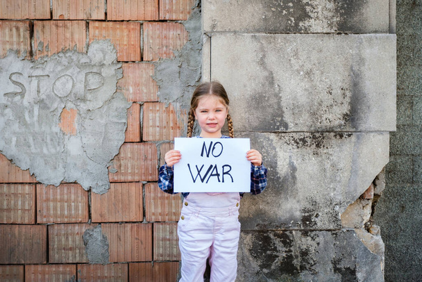 Девочка держит плакат с надписью "НЕТ ВОЙН" в поддержку мира. Концепция "никакой войны" на Украине и в мире. Российский конфликт в поддержку мира - Фото, изображение