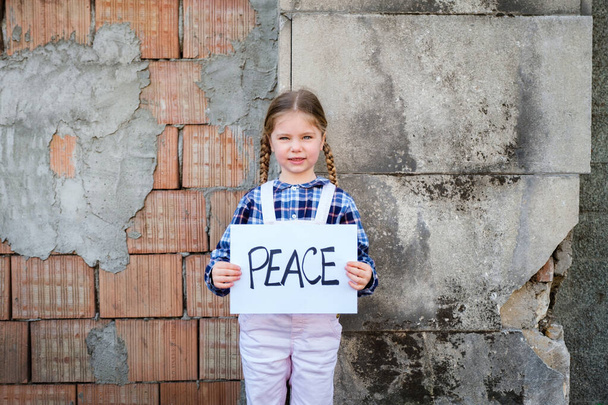 Dziewczynka trzymająca plakat z napisem POKÓJ na rzecz pokoju. Koncepcja "żadnej wojny" na Ukrainie i na świecie. Rosyjski konflikt na rzecz pokoju - Zdjęcie, obraz