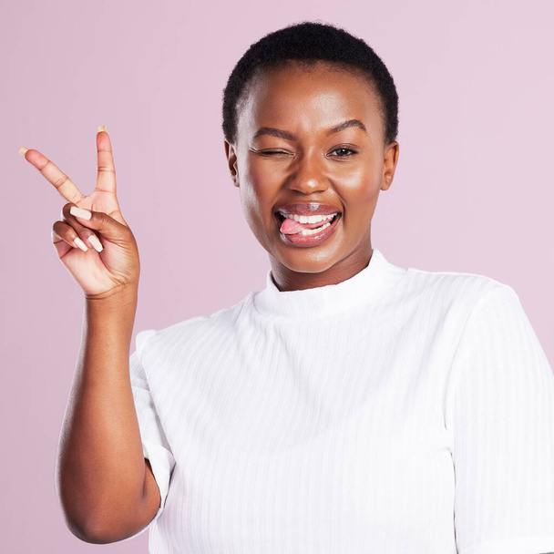 Good vibes only. Studio portrait of a young woman showing the peace sign against a pink background. - Foto, Imagen