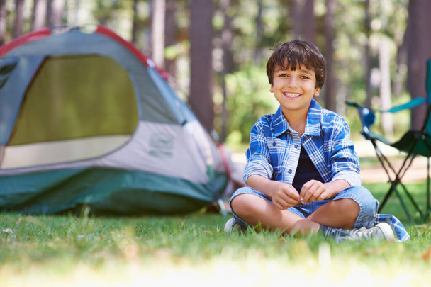 Nejlepší letní prázdniny na světě. Portrét mladého chlapce sedícího v lese před stanem. - Fotografie, Obrázek