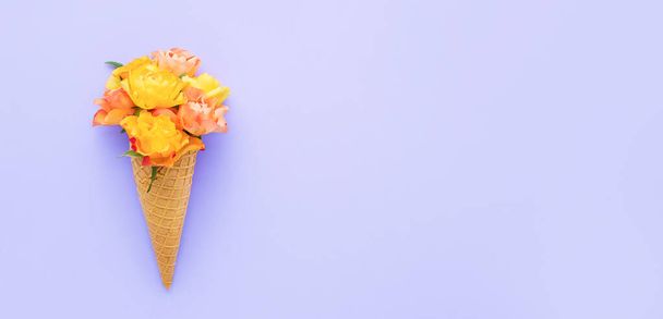 Yellow roses in a waffle ice cream cone on a lilac background. Summer concept, banner - Fotografie, Obrázek