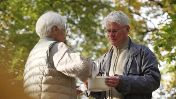 Běloch starší důchodce žena sdílí její domácí polévku s nezaměstnaným a bezdomovec starší muž v nouzi. - Záběry, video