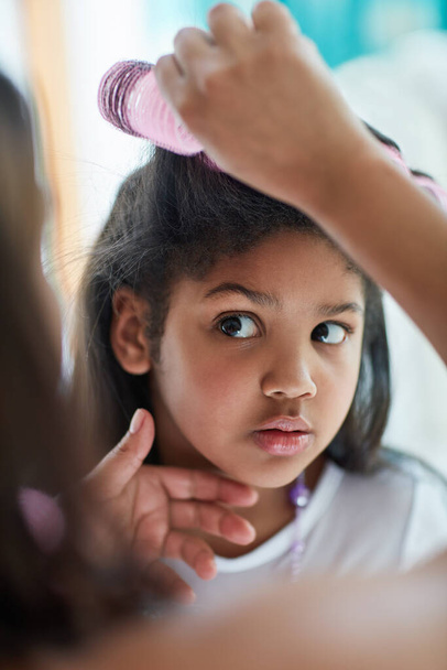 Are you sure about this, mom. Shot of a nervous little girl watching as her mother puts curlers in her hair. - Photo, Image