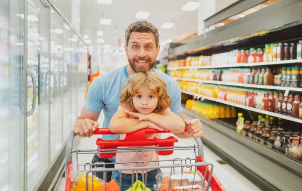 Amazed family father and child son with shopping cart buying food at grocery store or supermarket. Surprised face. Man shopper with groceries. - Φωτογραφία, εικόνα
