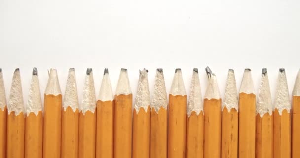 Panning w rzędzie używanych i zużytych żółtych ołówków ze złamanymi końcówkami ołówka, z jednym pojedynczym i niepowtarzalnym zaostrzonym ołówkiem. - Materiał filmowy, wideo