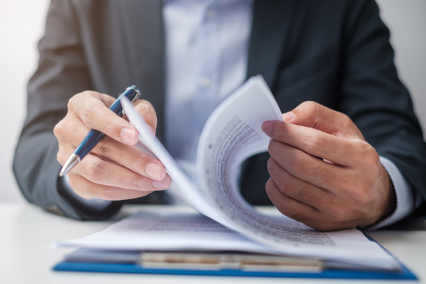Бизнесмен подписывает контрактные документы после прочтения, человек держит ручку и утверждает по деловому отчету. Контрактное соглашение, партнерство и концепция сделок - Фото, изображение
