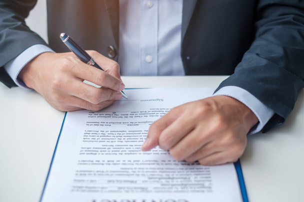 Businessman signing on contract documents after reading, man holding pen and approve on business report. Contract agreement, partnership and deal concepts - Фото, зображення