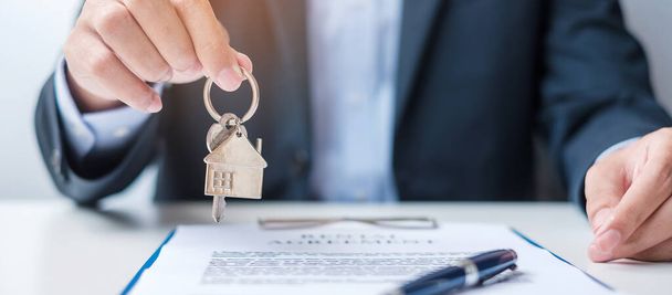 man holding home key during signing home contract documents. Contract agreement, real estate,  buy and sale and insurance concepts - Photo, Image