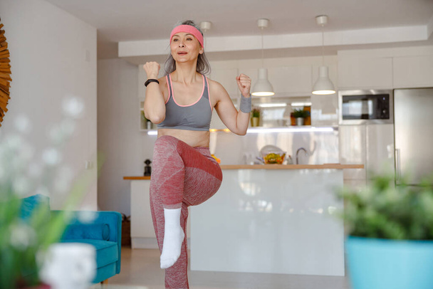Woman in sportswear having workout in living room - Foto, afbeelding