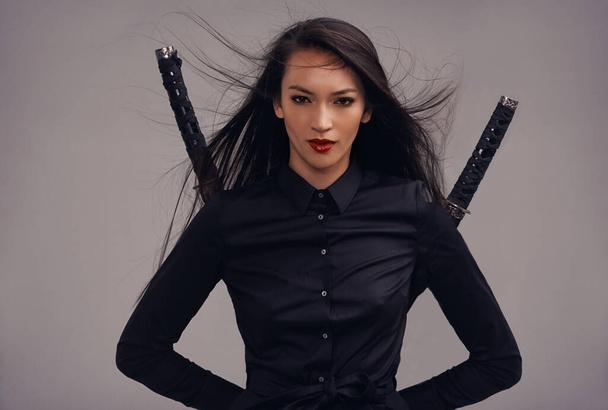 Upholding the samurai way. Cropped studio portrait of a beautiful young woman in a martial arts outfit wielding two samurai swords. - Photo, Image