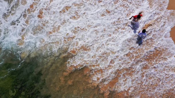 Αεροφωτογραφία παιδιών που παίζουν στην αμμώδη παραλία δίπλα στη θάλασσα, καλοκαιρινές διακοπές - Φωτογραφία, εικόνα