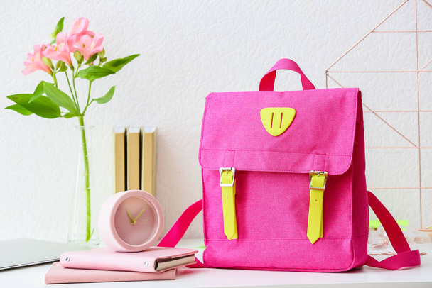 Стильный рюкзак, блокноты и будильник на столе - Фото, изображение