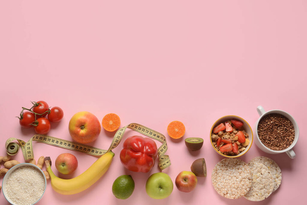 Zusammensetzung mit gesunden Produkten und Maßband auf rosa Hintergrund - Foto, Bild