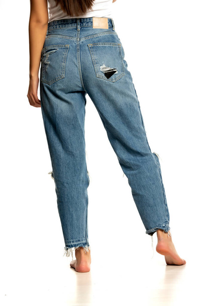 visão rara de uma perna de uma mulher em jeans de cintura alta em um fundo branco - Foto, Imagem
