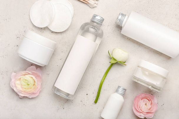 Ensemble de produits cosmétiques, tampons en coton et fleurs de ranunculus sur fond clair - Photo, image