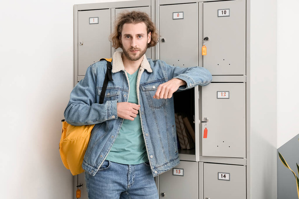Handsome male student near locker at the university - Foto, imagen
