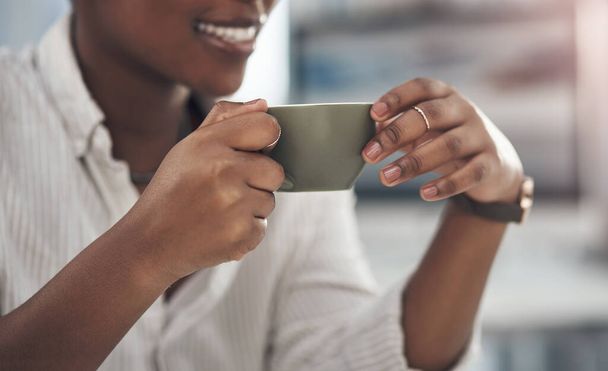 Coffee is my relaxing remedy. Shot of a businesswoman enjoying a cup of coffee at work. - Foto, Bild