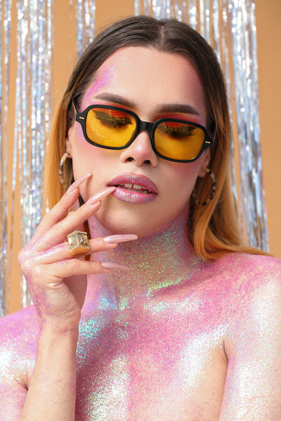 Fashionable young transgender woman with glitters on body against color background - Фото, зображення