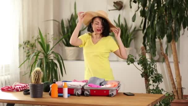 Ευτυχισμένη γυναίκα στο χορό καπέλο, συσκευασία βαλίτσα, ετοιμάζεται για το ταξίδι των καλοκαιρινών διακοπών προετοιμασία των αποσκευών για ταξίδια διακοπών. - Πλάνα, βίντεο