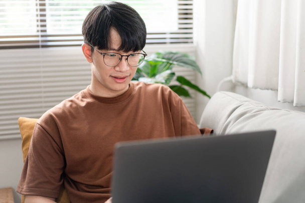 技術の概念ガラスの上に置かれている男は、ノートパソコンの画面に焦点を当てながら、暗い黄色に背中を傾け. - 写真・画像