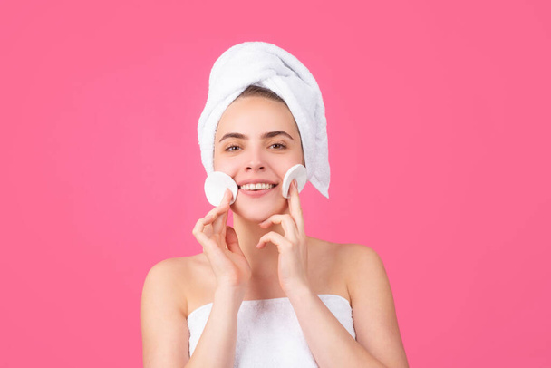 Beautiful smiling girl with clean fresh skin. Facial treatment. Cosmetology beauty and spa. Cream on face, woman wrap towel on head put facial creme on healthy skin. - Photo, image
