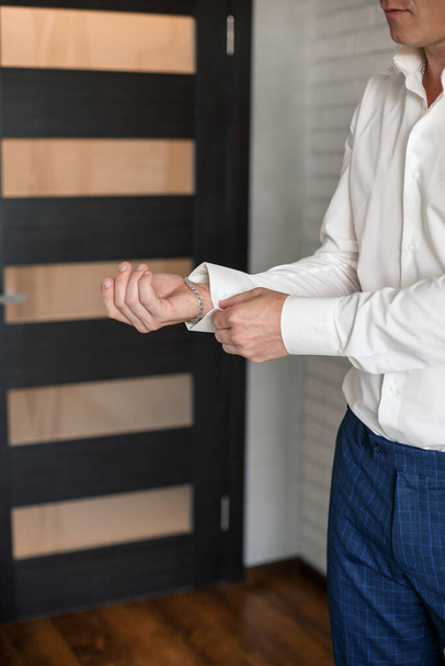 Homme d'affaires boutonnant un bouton sur la manche d'une chemise blanche - Photo, image