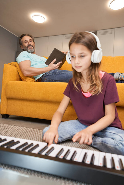 Підліток у вітальні натискає клавіші синтезатора
 - Фото, зображення
