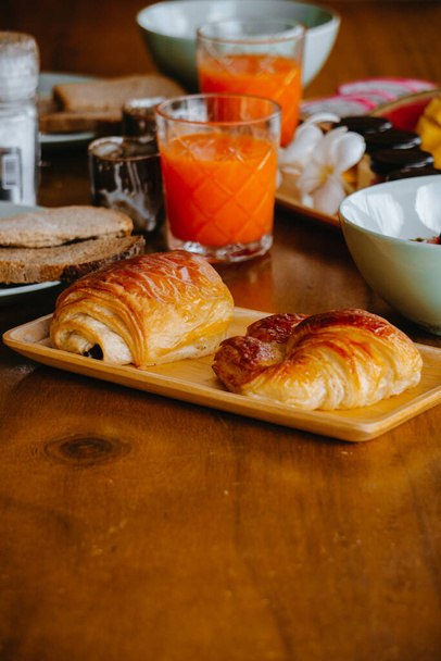Chléb a croissanty v podnosu s ovocnou šťávou v pozadí. - Fotografie, Obrázek