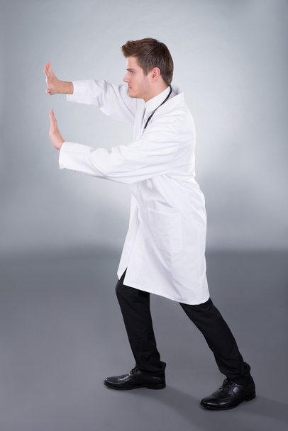 Doctor Pushing Invisible Wall - Foto, afbeelding