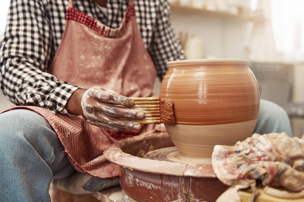 Craftsperson applying glaze to earthenware jar using hake brush - Фото, изображение